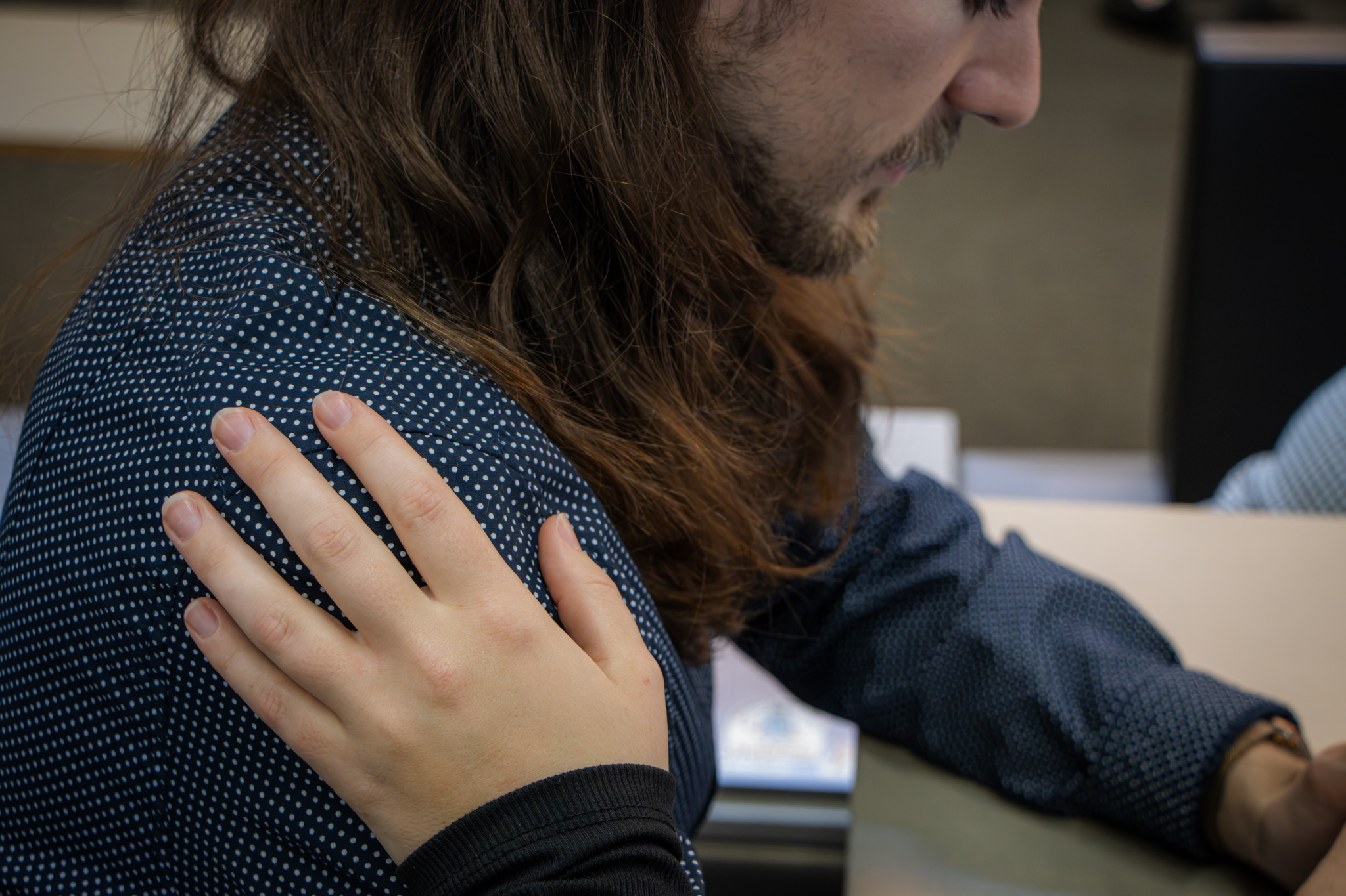 Student being comforted by other student placing their hand on their shoulder