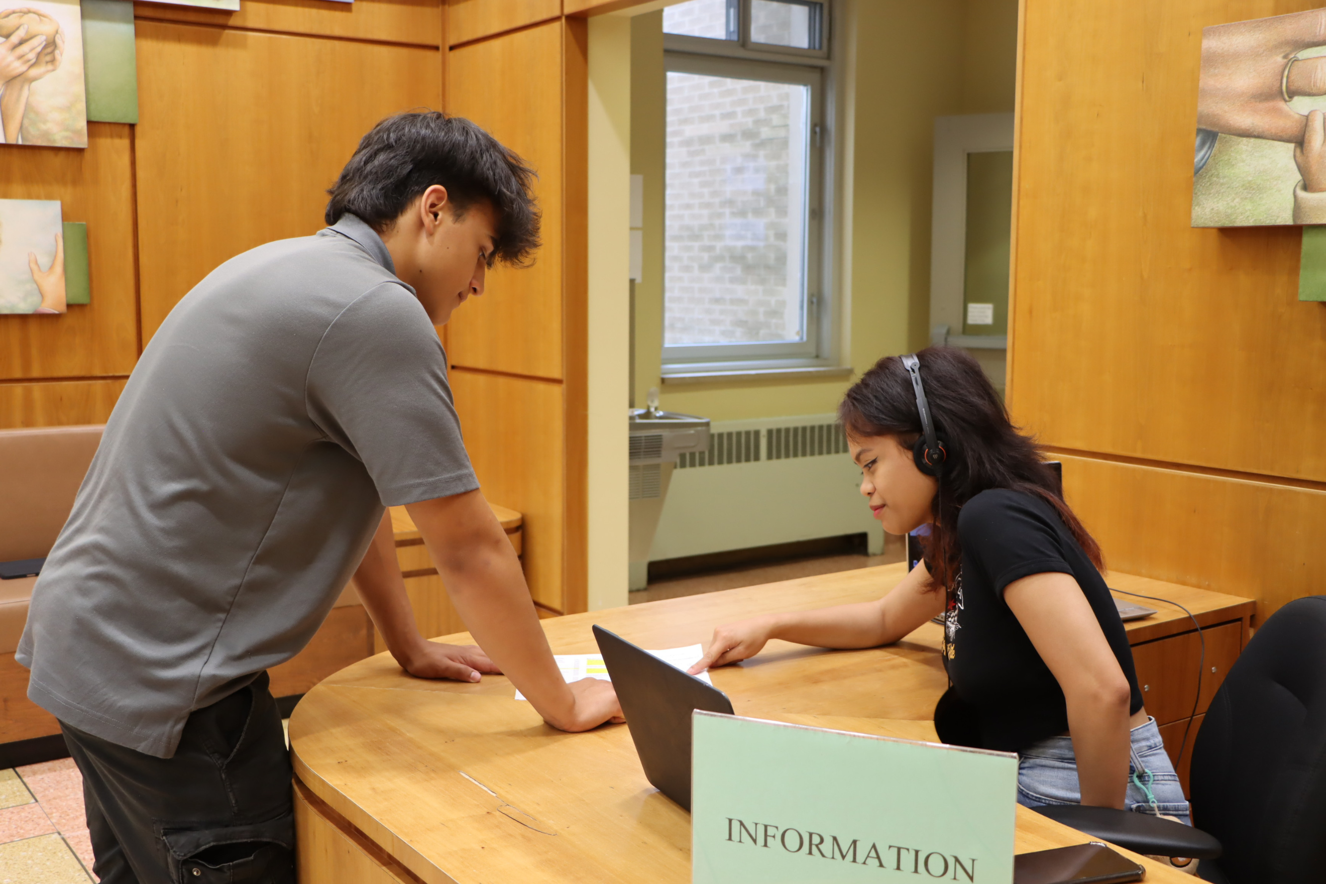 Work-study student working at a desk and helping another student